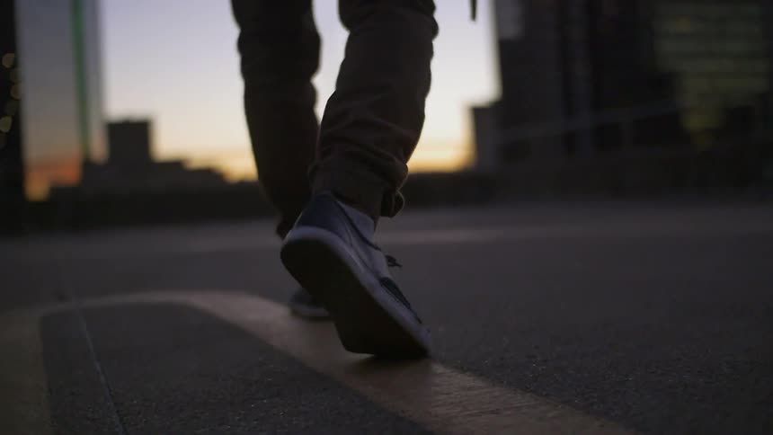 Person walking on pavement at sunset