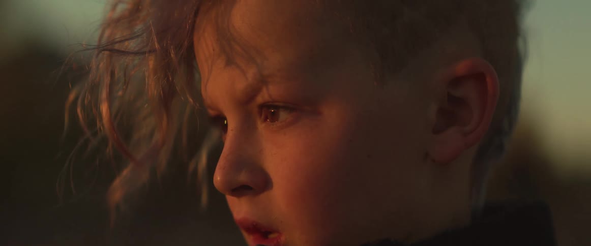 A boy is outside at sunset
