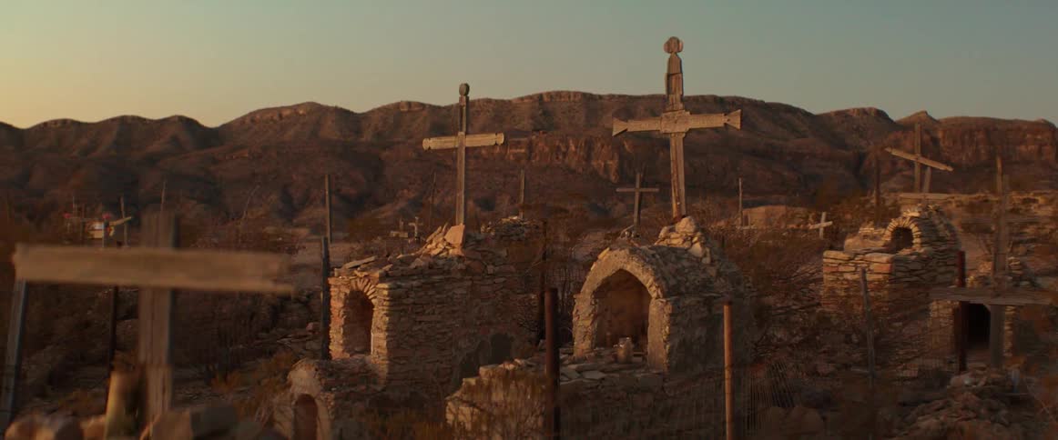A cemetery with many graves and crosses on top with mountains and hills in the background