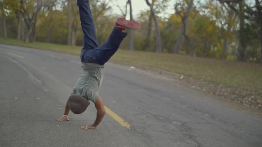 A man performs a cartwheel in the street