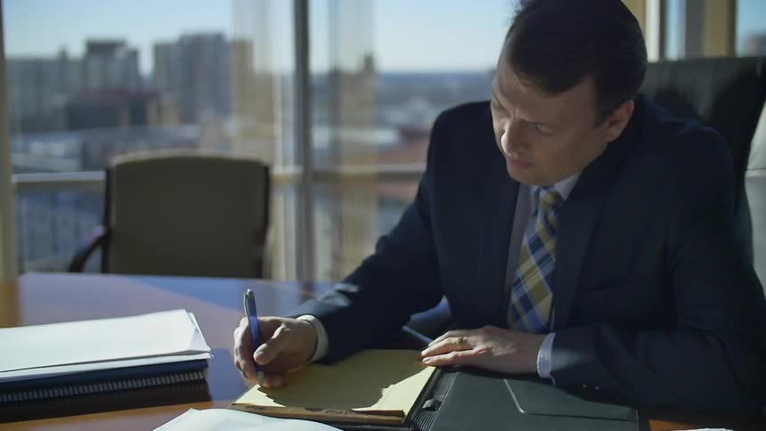 A man sitting at a desk writing on a notepad