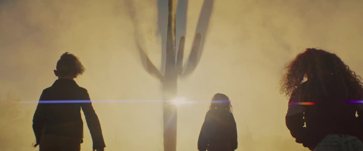 Three people walk into a smokefilled environment at sunset