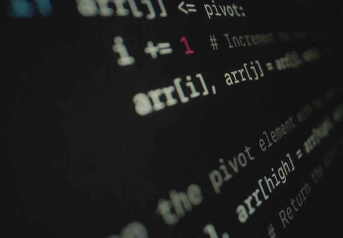 A closeup of a computer screen displays lines of code with highlighted syntax and comments