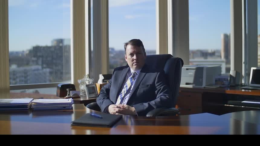 A man sits at an executive desk in his office