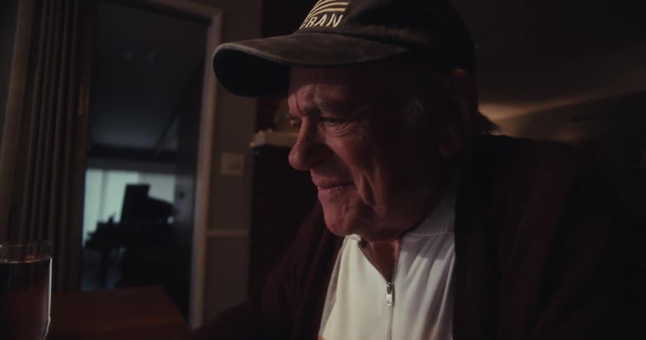 Elderly man smiles while using a computer at home