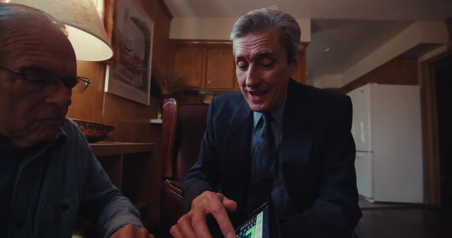 A man points to the tablet while talking with a man