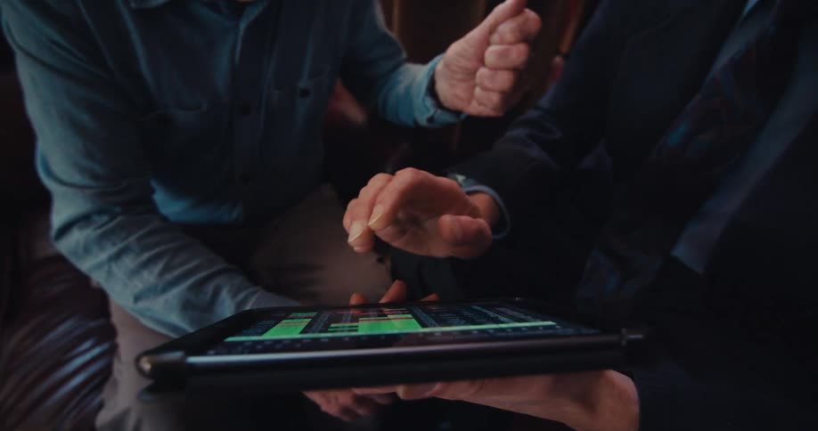 Two men look at graphs on the tablet