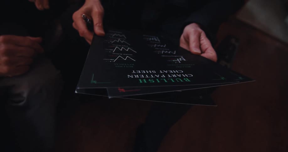 Two individuals are reviewing financial charts printed on a black surface at home
