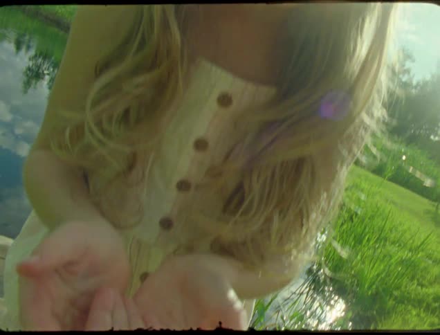 Kids examine a ladybug while exploring near a pond on a summer day