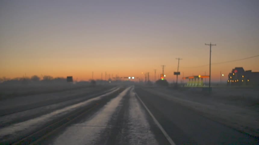 A vehicle drives on a road at sunset
