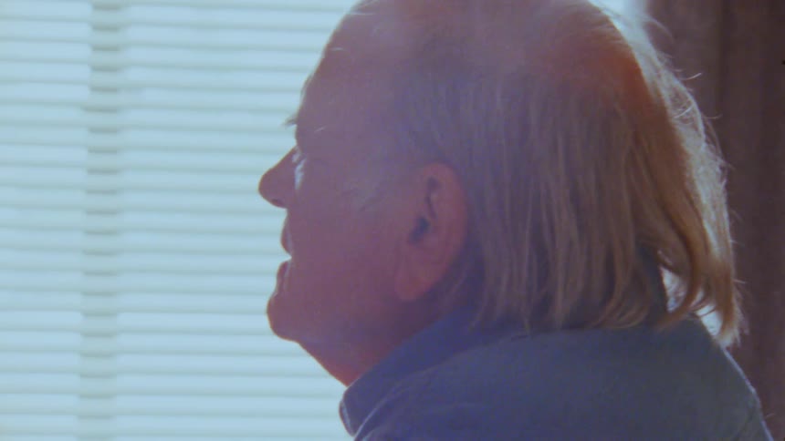 The man is pointing and talking by the window