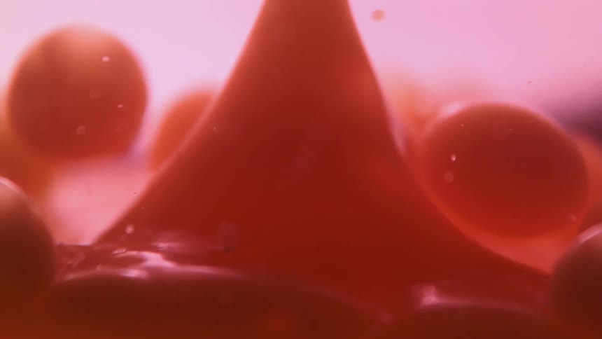 Colored liquid bubbles fall into clear liquid