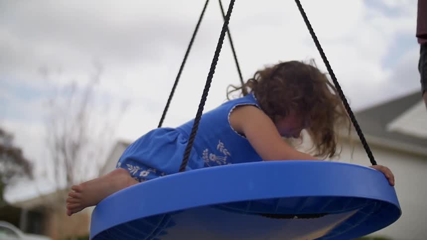 Little girl smiles on a swinging disk