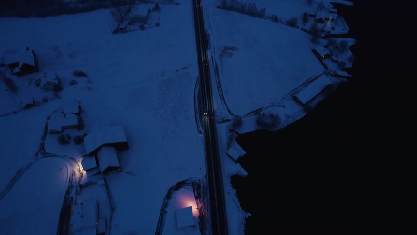 Cars drive on the road through town at night