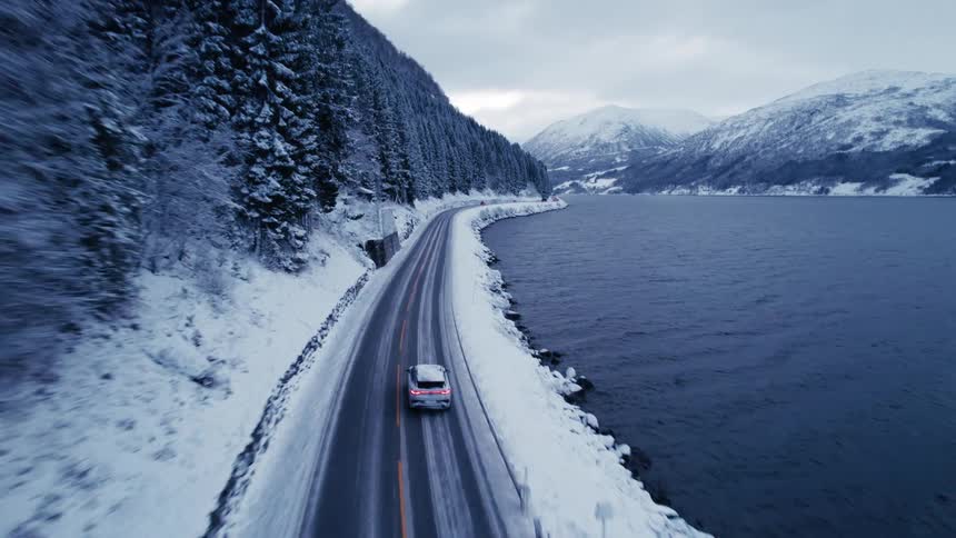 The car drives by the cottages in the snow