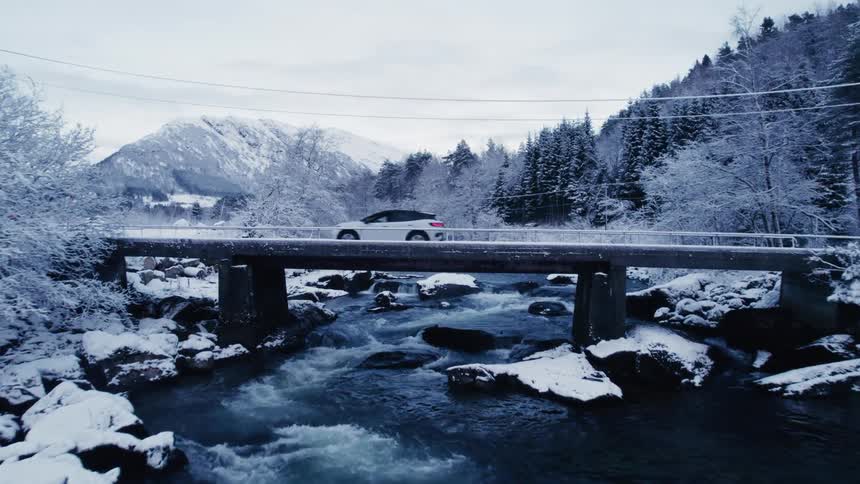 A car drives over a small bridge by the mountain