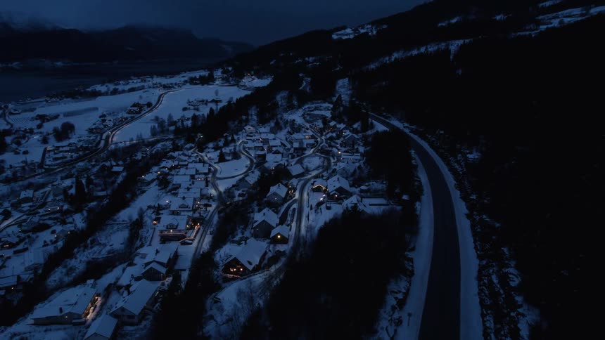 Aerial night view of a village and a freeway by the sea