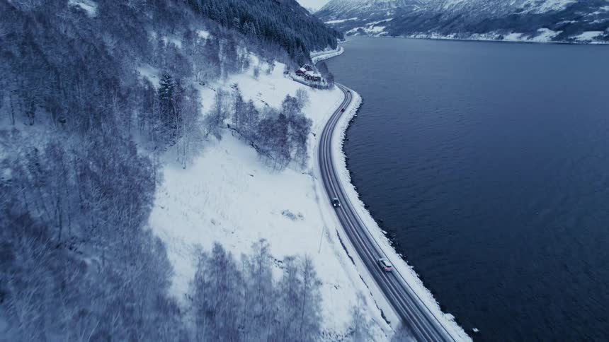 Aerial view of cars driving on the freeway near a lake and some mountain ridges