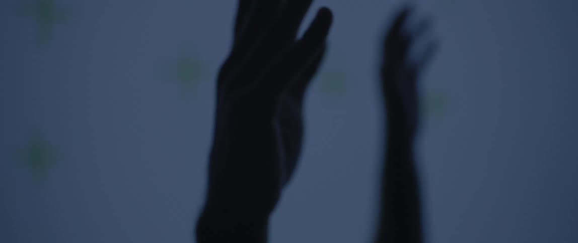 A person has their hands raised in the dark room