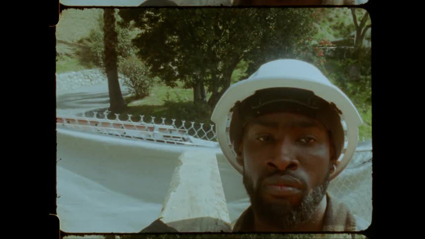 A construction worker in a hard hat looks down appearing focused