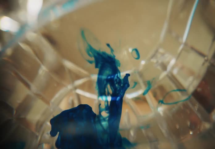 Ink is being mixed into a glass of water with a spoon