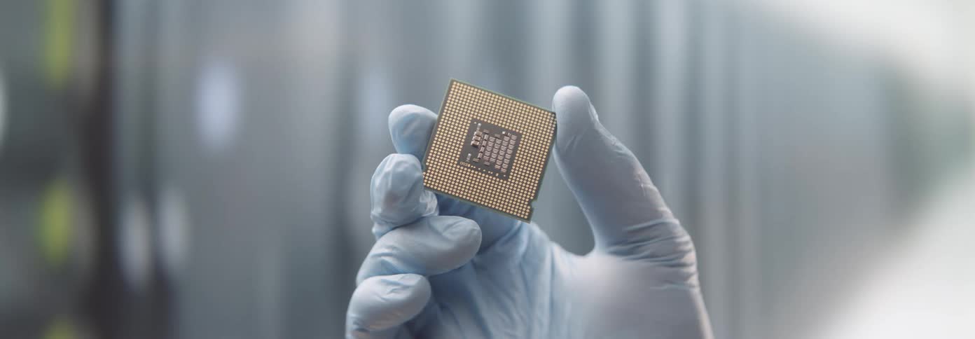 A persons hand wearing a blue glove is holding and inspecting a computer cpu