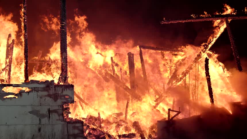 Structure of a building engulfed in flames in slow motion at night