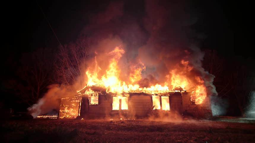 House in a rural area engulfed in flames at night