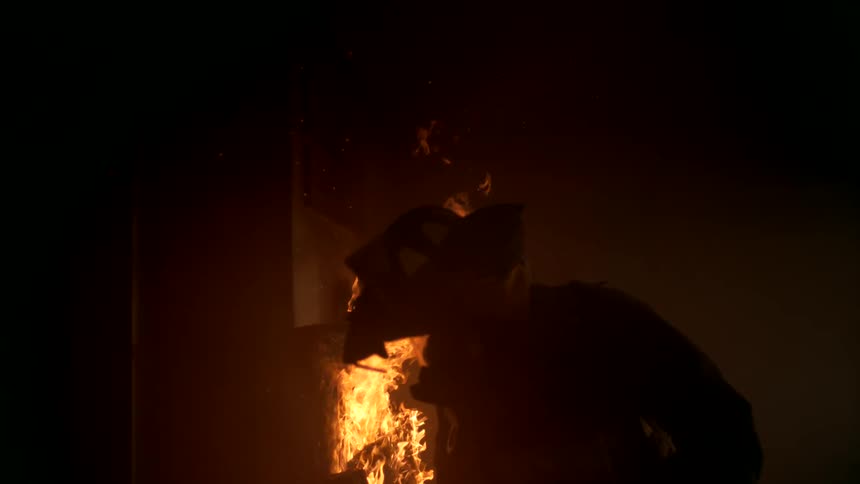 A firefighter walking inside a burning house