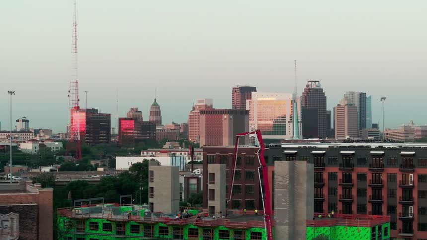 A city with many residential and commercial buildings cars driving on the road and birds flying in the sky