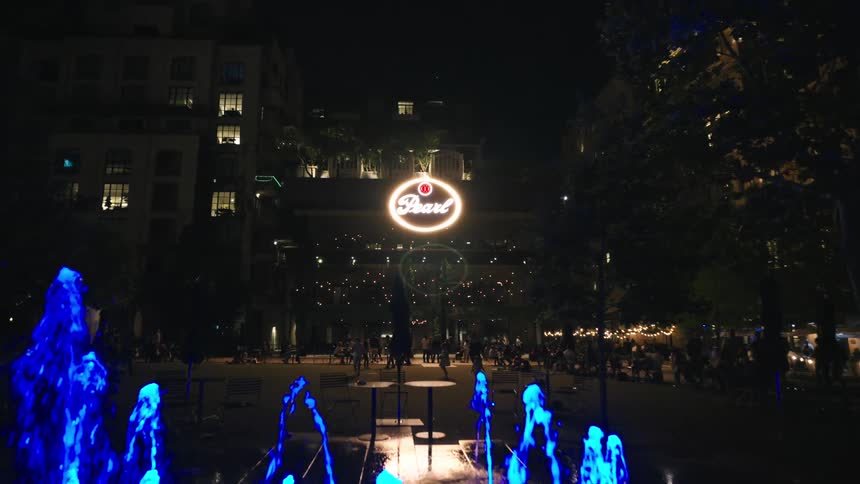 People are walking around the city square at night