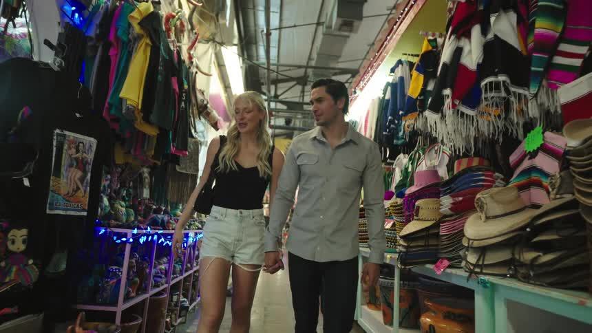A couple walk down the store aisle while talking