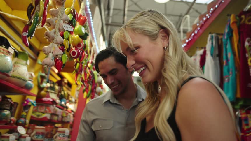 A smiling couple shares a joyful moment while shopping in a colorful marketplace