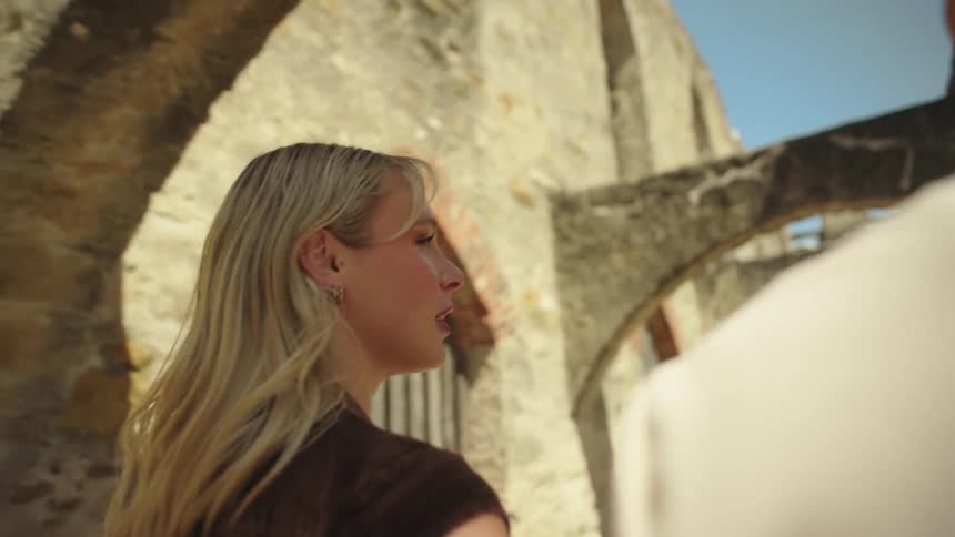 Couple smiles while walking through an old building on a summer day