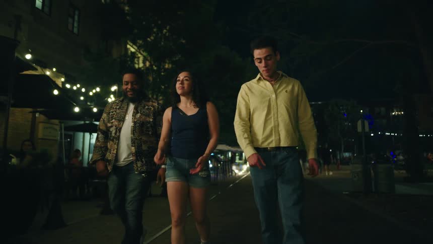Three friends are walking in the city while talking to each other