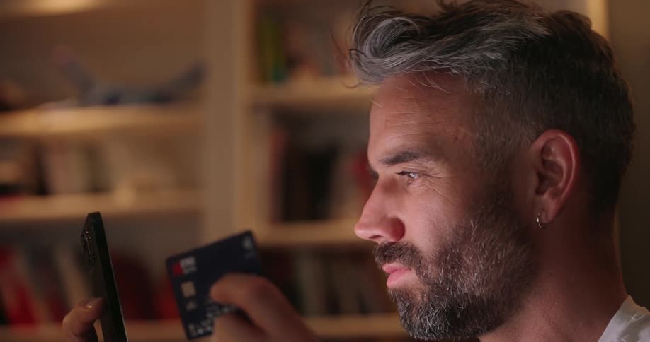 Man uses a credit card while shopping on his smartphone