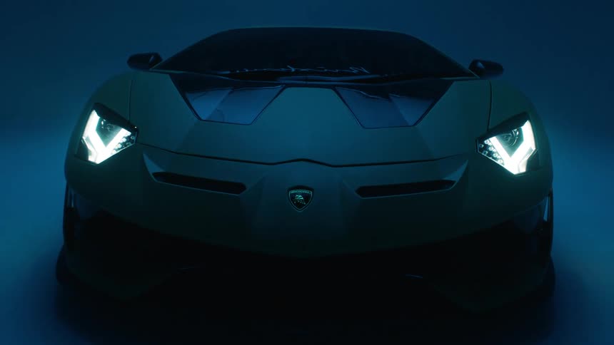 A sleek modern sports car with its headlights on illuminated by flashing blue and red lights in a dimly lit room