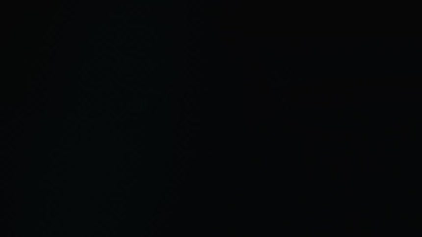 The hood of a lamborghini is seen in a dark room with flickering blue light