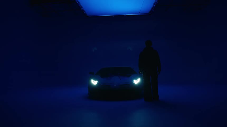 A man walking toward a car and touching it