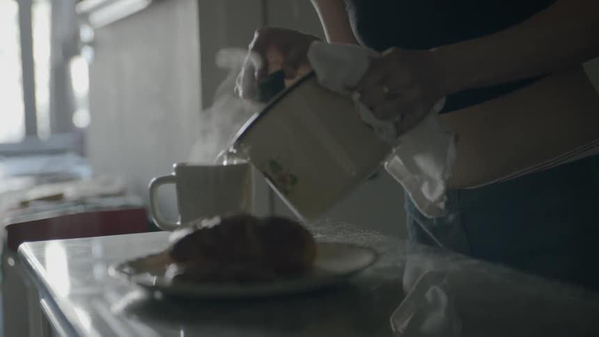 A woman pours boiling water into a cup