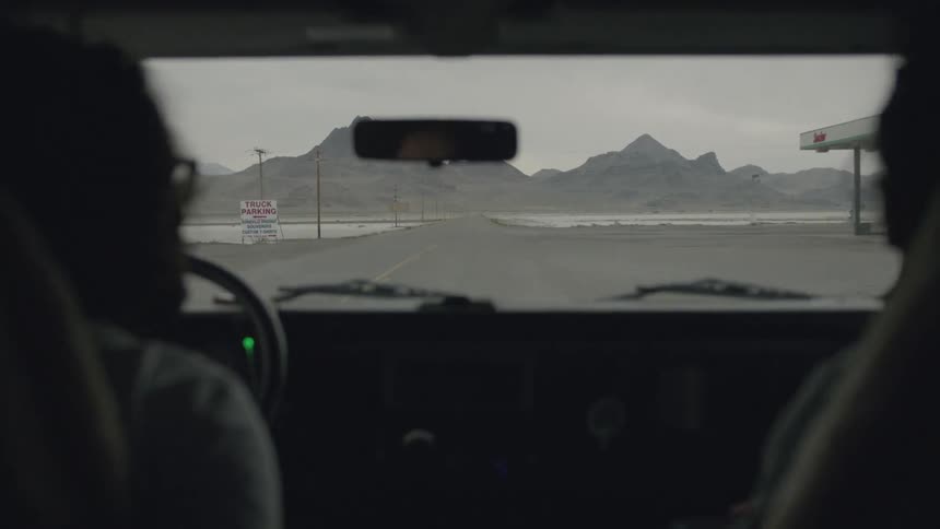 Two people drive down road inside a vehicle