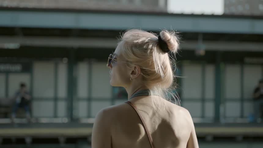 A woman dances while waiting at a train station