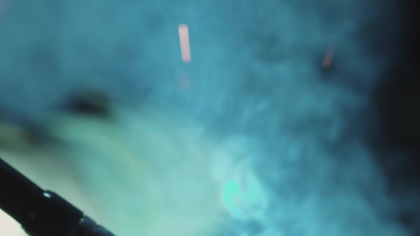 Smoke and sparks fly as a piece of metal is being welded