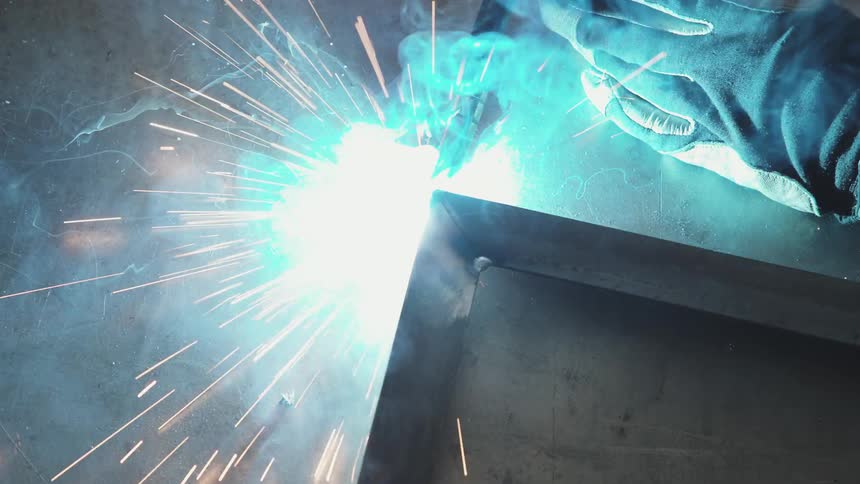 A person using a welding machine to weld two iron bars together