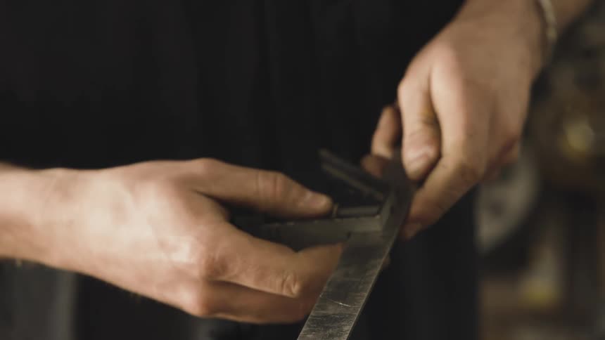 Pair of hands handling a ruler and a tool