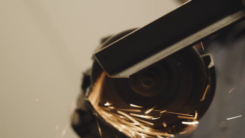 A closeup shot captures sparks flying as a person grinds a piece of metal with a power tool