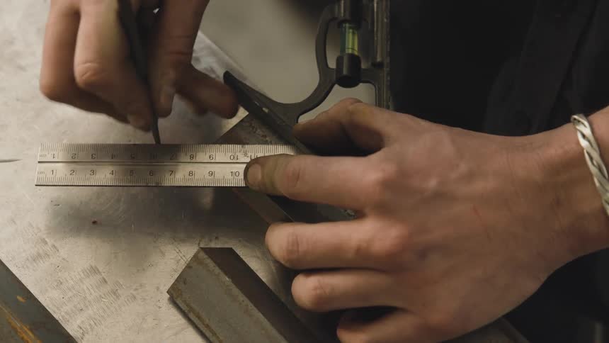 Hands are shown using a ruler square and pencil to mark a piece of metal