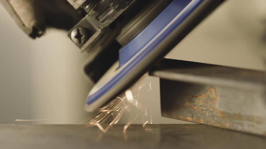 A machine with a rotating disk scraping against a metal object giving off many bright sparks