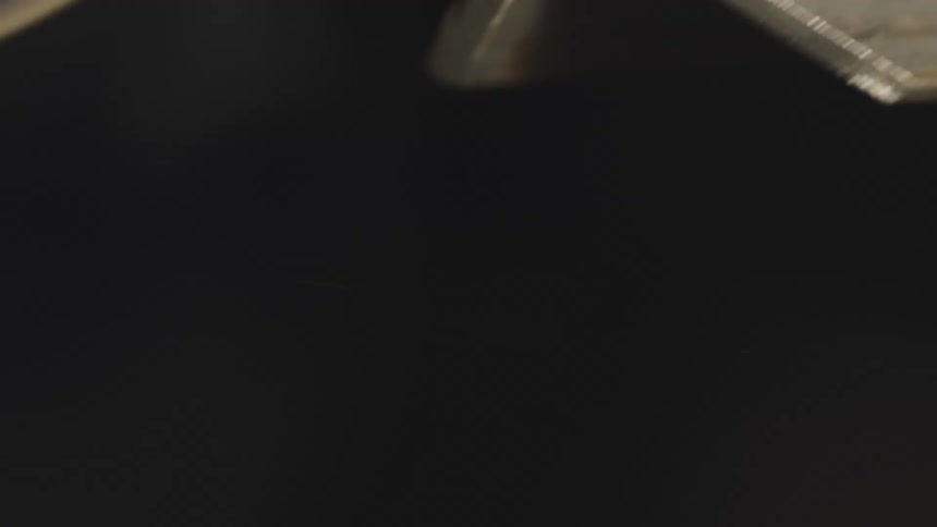 A rotating disk tool scraping the surface of an iron object and releasing several shiny streaks