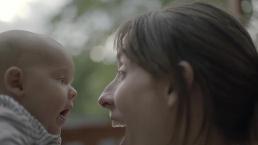 A woman lifts a baby to her face smiling